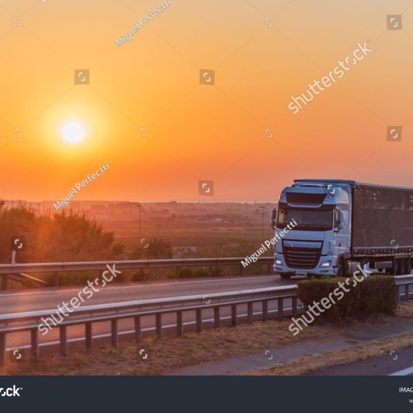 stock-photo-curtainside-semi-trailer-truck-for-general-cargo-driving-on-a-highway-at-sunrise-2650046609