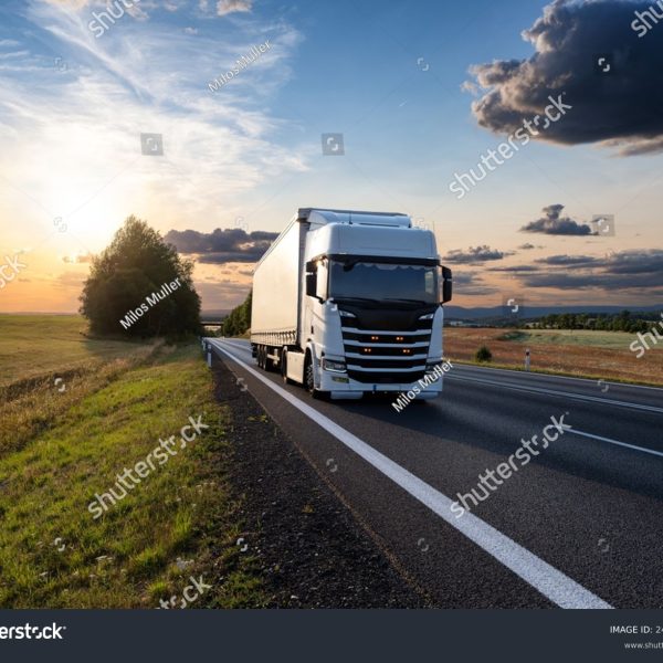 stock-photo-white-truck-driving-on-the-asphalt-road-in-rural-landscape-at-sunset-2469501197